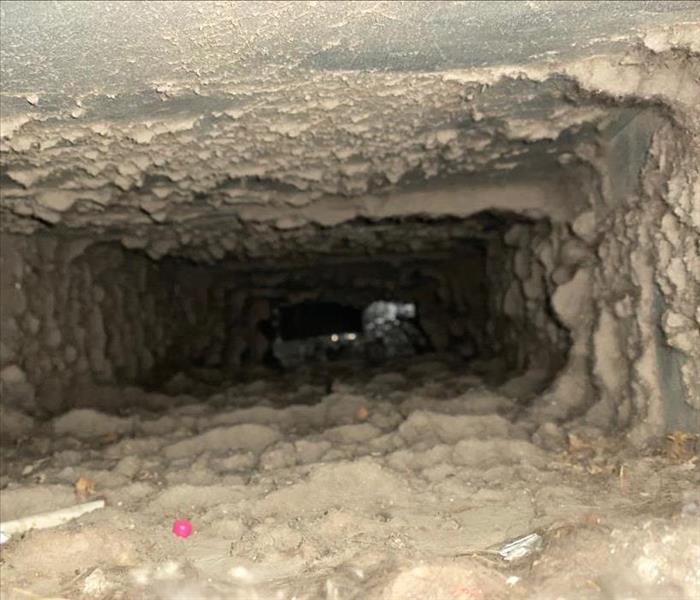 Interior view of metal air duct which has a substantial amount of dust, dirt and debris.