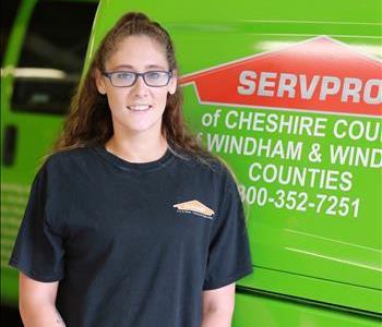 A female SERVPRO technician standing in front of a green SERVPRO van