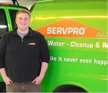 Image of male SERVPRO employee standing in front of green SERVPRO van.