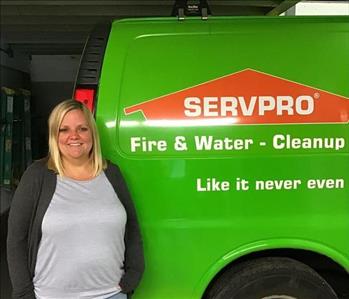 A woman standing next to a green SERVPRO van