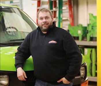 A man standing in front of a green SERVPRO van