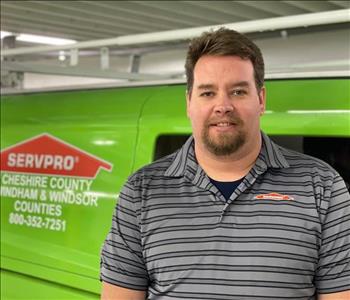 Male employee standing in front of green SERVPRO van.
