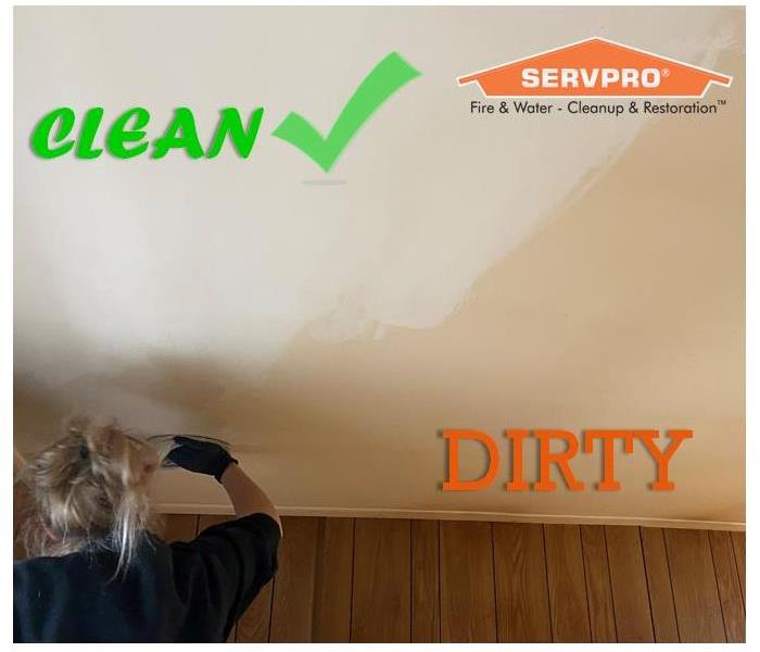 SERVPRO employee scrubbing a dirty ceiling with a cleaning rag showing drastic difference of cleaned and not cleaned areas.