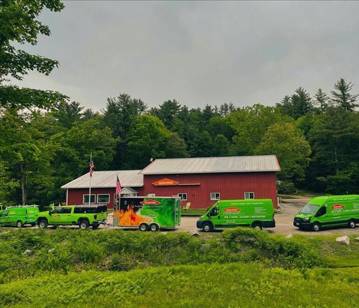 Exterior photo of large red building and several green trucks parked around the exterior.